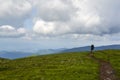 Rear view man hiker with backpack walking along a hiking path towards the top of the mountain Royalty Free Stock Photo