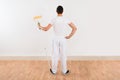 Rear View Of Man Holding Paint Roller Against White Wall Royalty Free Stock Photo