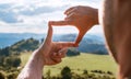 Rear view of Man looking at mountain landscape framing with fingers, searching for best image composition as he hiking over the