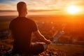 Rear view of the man meditating yoga in lotus pose on the rock at sunset. Royalty Free Stock Photo