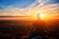 Rear view of the man meditating yoga in lotus pose on the rock at sunset. Royalty Free Stock Photo