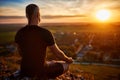 Rear view of the man meditating yoga in lotus pose on the rock at sunset. Royalty Free Stock Photo