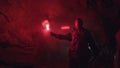 Rear view of a man with red burning signal flare going towards light to to get out of the cave. Stock footage Royalty Free Stock Photo