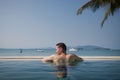 Rear view man while relaxing in swimming pool against sea Royalty Free Stock Photo