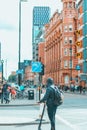 Rear view of a man riding a scooter on the street of Manchester City Centre, UK