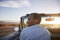 Rear View Of Man On Road Trip Driving Classic Convertible Car Towards Sunset Royalty Free Stock Photo