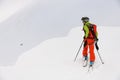 rear view of man skier with trekking poles walking along snowy mountain slope Royalty Free Stock Photo