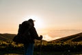 Rear view man standing on the hill with hiking backpack and sticks Royalty Free Stock Photo