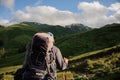 Rear view man standing on the hill with hiking backpack and sticks looking at the landscape Royalty Free Stock Photo