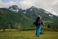 Rear view man standing on the hill looking at rocky mountains covered with grass with the snow remnants Royalty Free Stock Photo