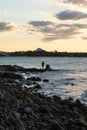 Rear View of Man Standing on Rocks in front of the Ocean Watching the Sunset. Traveler Concept Royalty Free Stock Photo