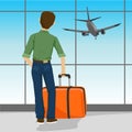 Rear view of man standing with suitcase in airport watching landing aircraft Royalty Free Stock Photo