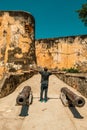 Rear view of man standing between two ancient canons at the entrance of Fort Jesus in Mombasa, Kenya Royalty Free Stock Photo