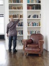 Rear View Of Man Taking Book From Shelf