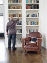 Rear View Of Man Taking Book From Shelf