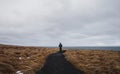 Rear view a man walking alone on footpath in dried field Royalty Free Stock Photo