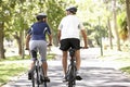 Rear View Of Mature Couple Cycling Through Park