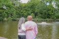 Rear view of a mature couple embracing, contemplatively looking at a fountain in a pond Royalty Free Stock Photo
