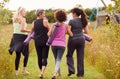 Rear View Of Mature Female Friends On Outdoor Yoga Retreat Walking Along Path Through Campsite Royalty Free Stock Photo