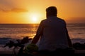 Rear view of mature man in front of a magnificent orange sunset at sea. Bicycle by his side