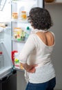 Rear view of mature woman looking in fridge at kitchen Royalty Free Stock Photo