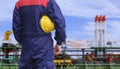 Rear view of engineer holding yellow safety helmet with blurred crude oil tanker in shipyard area Royalty Free Stock Photo
