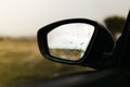 Rear view mirror seen through the glass. Wet car window. Close up rain drop. Car view see the mirror Royalty Free Stock Photo