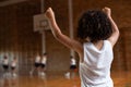Schoolboy cheering with arms up in the basketball court