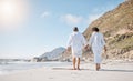 Rear view of a Mixed race senior couple taking a romantic walk on the beach and holding hands on a sunny summer day Royalty Free Stock Photo