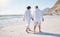 Rear view of a Mixed race senior couple taking a romantic walk on the beach and holding hands on a sunny summer day Royalty Free Stock Photo