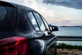 Rear view of modern luxury black car parked above the sea with a romantic view during the sunset Royalty Free Stock Photo