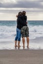 Rear view of mother and daughter standing hugging on the beach. Vertical shot Royalty Free Stock Photo