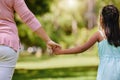 Rear view of mother holding her daughters hand in a park. Mixed race single parent enjoying free time with child outside Royalty Free Stock Photo