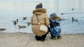 Rear view of mother with little boy feeding ducks on cold winter day at park Royalty Free Stock Photo