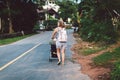 Rear view Mother strolling with toddler by countryside the street Journey with kid. Every day of mum, maternity daily Royalty Free Stock Photo