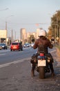 Rear view at motorbiker with motorcycle standing on urban road, female rider is ready to start movement in city