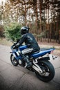 Rear view of motorcycle driver driving in helmet with blurred forest background