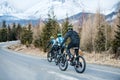 Rear view of mountain bikers riding on road in mountains outdoors in winter. Royalty Free Stock Photo