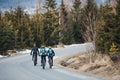 Rear view of mountain bikers riding on road in mountains outdoors in winter. Royalty Free Stock Photo
