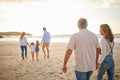 Rear view of Multi generation family holding hands and walking along the beach together. Caucasian family with two Royalty Free Stock Photo