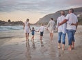 Rear view of Multi generation family holding hands and walking along the beach together. Caucasian family with two Royalty Free Stock Photo