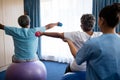 Rear view of nurse training seniors in lifting dumbbells Royalty Free Stock Photo