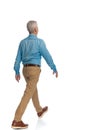 Rear view of old man with blue denim shirt and chino pants walking Royalty Free Stock Photo