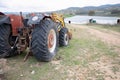 Rear view of an old tractor to work the land of the agricultural field, with a farm in the background Royalty Free Stock Photo