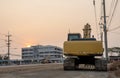 Rear view of an old yellow backhoe parked on a roadway being renovated