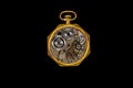 Rear view of an open antique mechanical pocket watch on isolated black background. Golden retro timepiece with mechanism