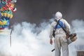 Outdoor healthcare worker using fogging machine spraying chemical to eliminate mosquitoes at Chinese shrine