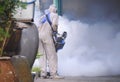 Outdoor healthcare worker using fogging machine spraying chemical to eliminate mosquitoes and prevent dengue fever at slum area