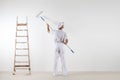 Rear view of painter man looking at blank wall, with paint stick Royalty Free Stock Photo