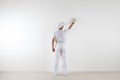 Rear view of painter man looking and painting blank wall, with p Royalty Free Stock Photo